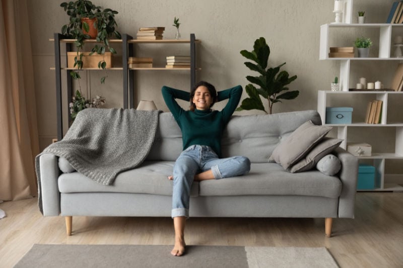 Man with arms behind his head sitting on a couch.